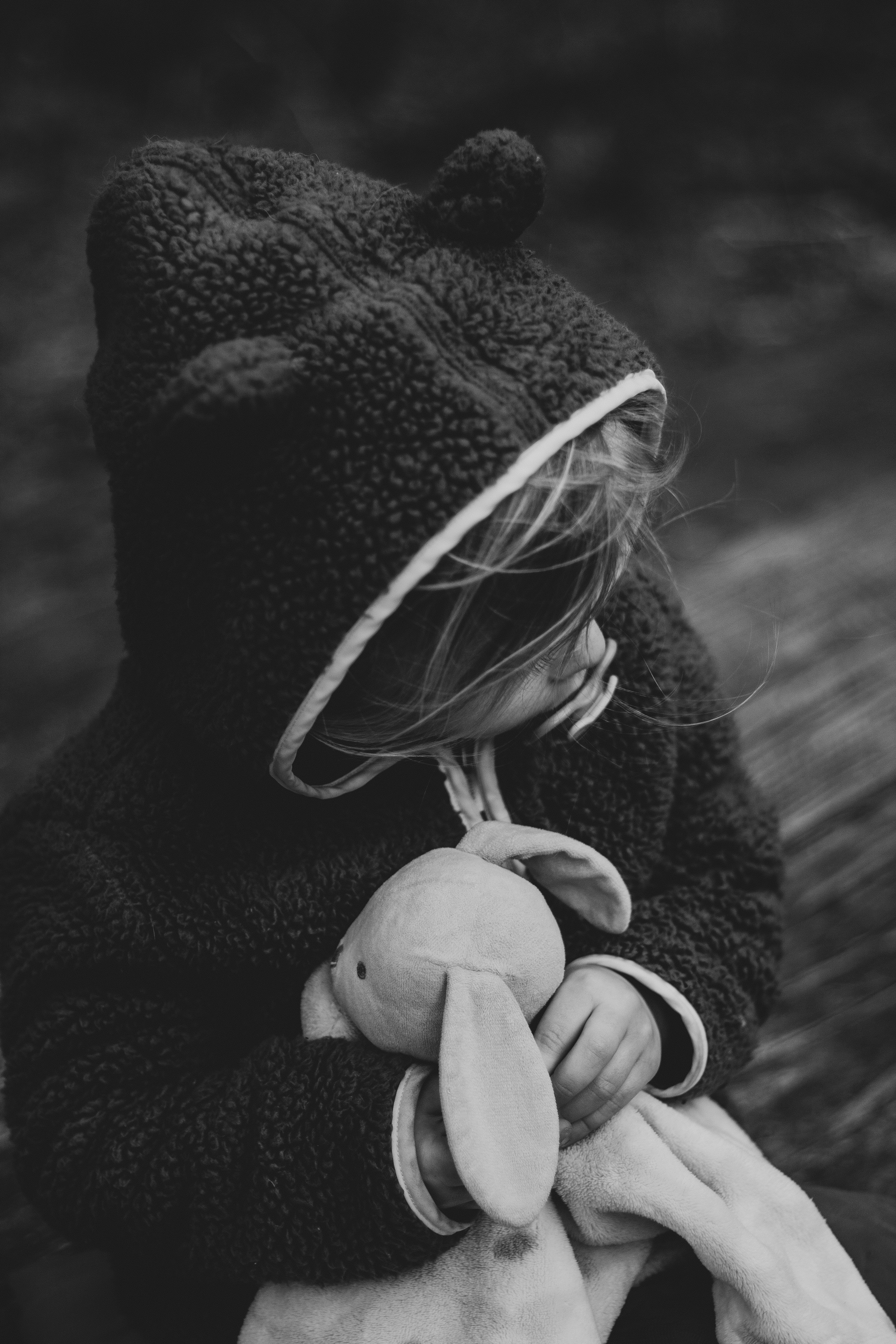 person in black hoodie holding white and black headphones